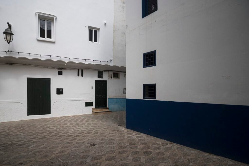 A quiet white and blue alley in the medina of Asilah with a lantern on the wall