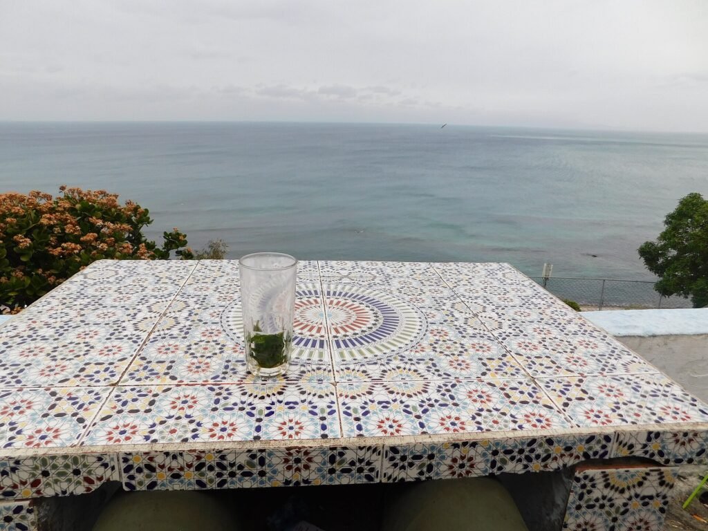 Mint tea on a tiled table at Café Hafa in Tangier with the sea behind, a classic stop on a Tangier day trip from Spain