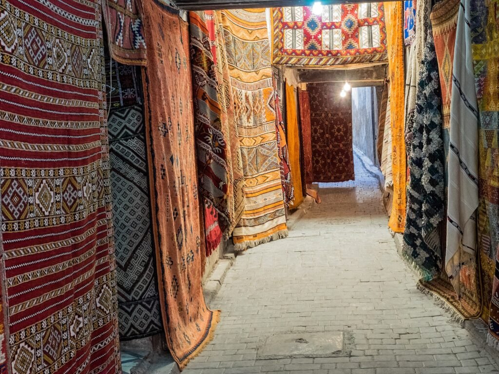 A narrow alley hung with colourful carpets in the souks of Fes