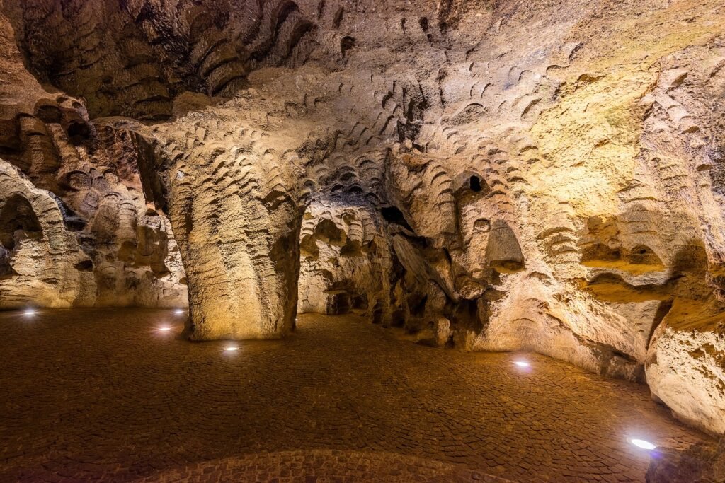 The lit interior of the Caves of Hercules with carved walls