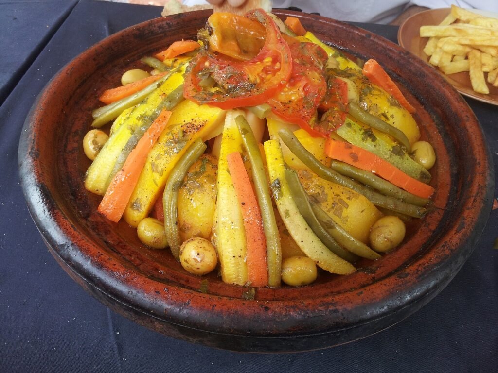 A vegetable tagine in a terracotta dish with carrots, potatoes and green beans